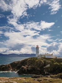 Lighthouse by sea against sky