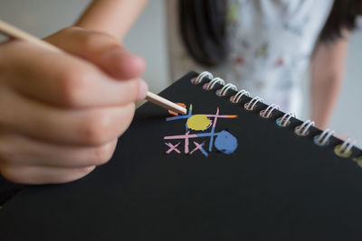 Midsection of girl painting on notepad