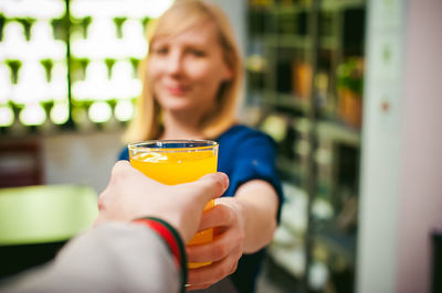 Cropped hand of man taking drink from woman at home