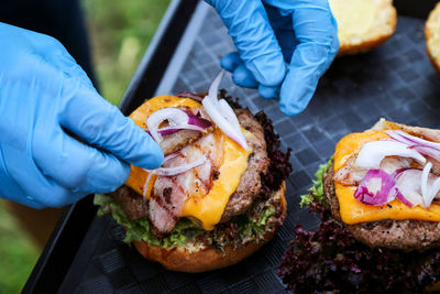 Cropped hands of vendor preparing burgers at market stall