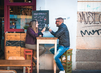 Couple holding wineglasses on table talking while sitting at outdoor cafe