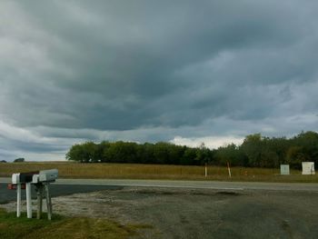 View of field against cloudy sky