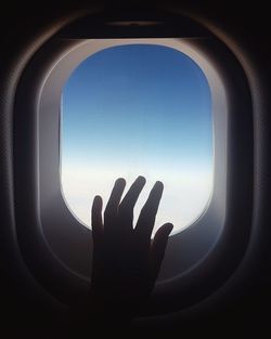 Cropped hand touching window of airplane