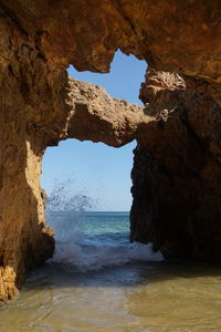 Rock formation on beach against sky