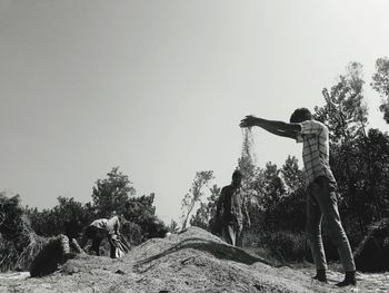 Rear view of man standing on rock against sky