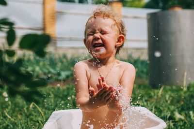 Cute shirtless girl splashing water outdoors