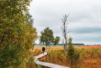 Man sitting by plants against sky during autumn