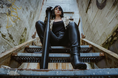 Portrait of woman sitting on staircase against wall