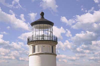 Low angle view of lighthouse by building against sky