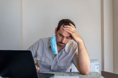 Frustrated man wearing flu mask sitting at office