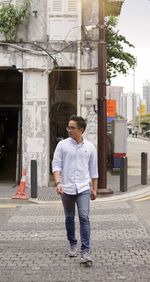 Full length of young man standing on footpath