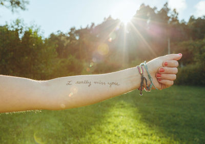 Cropped hand of woman showing text written on forearm at park
