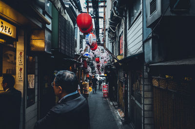 Rear view of man on street amidst buildings in city