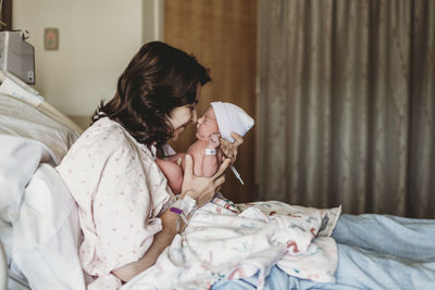 Side view of mother and newborn son touching noses in hospital