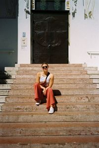 Full length of couple sitting on staircase against building