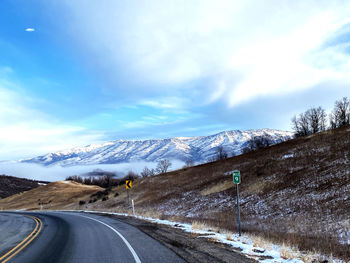 Road leading towards snowcapped mountains against sky