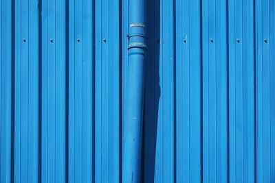 Close-up of blue pipe and metal wall