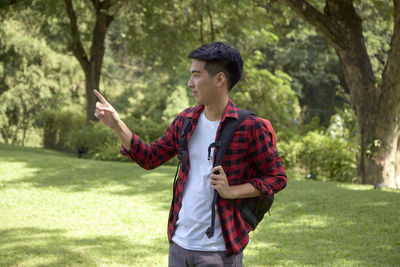 Full length of young man using phone while standing on grass