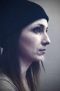 Side view of mid adult woman looking away while standing against wall