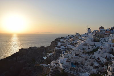 Aerial view of townscape by sea against sky during sunset