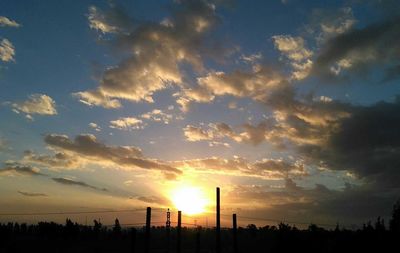 Silhouette of factory against sky during sunset