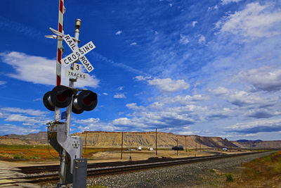 Low angle view of railroad crossing sign against sky