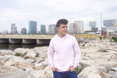 Young man standing on shore against sky