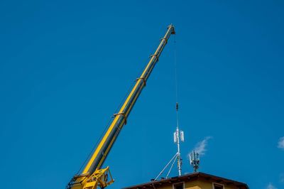 Low angle view of crane against clear blue sky