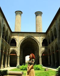 Woman standing by historic building against sky