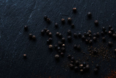 High angle view of fresh black peppercorns on dark surface 