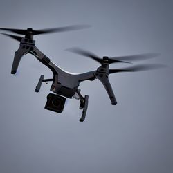 Low angle view of drone flying against clear blue sky