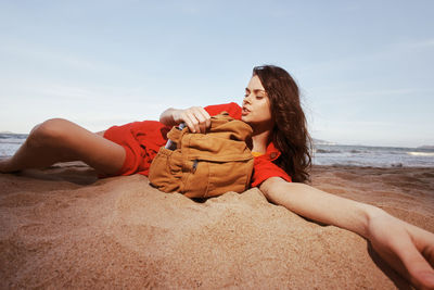 Low section of woman sitting on sand at beach