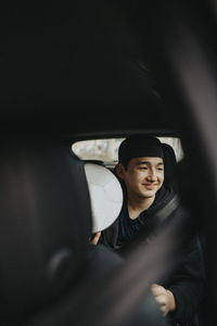 Smiling teenage boy with sports ball sitting in car