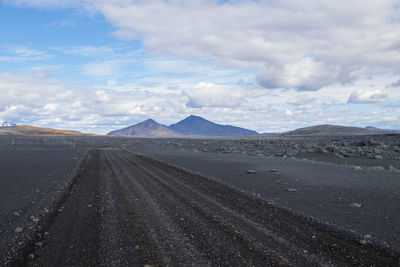 Road leading towards mountains against sky