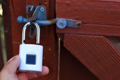 Close-up of hand holding padlock on door