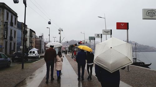 Rear view of people walking on city street during rainy season