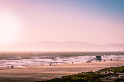 Scenic view of beach against clear sky during sunset