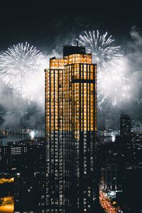 Firework display over illuminated buildings in city at night