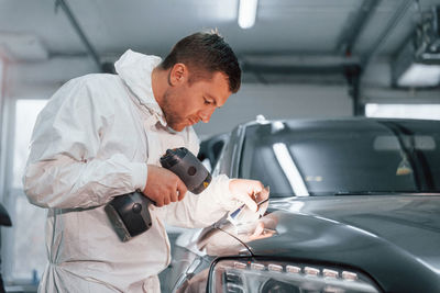 Using special equipment. man in uniform is working in the auto service.