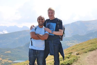 Portrait of friends standing on mountain against mountains