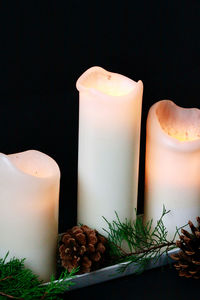 Close-up of lit candles on table against black background