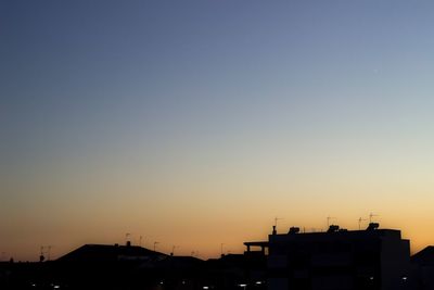 Silhouette buildings against clear sky during sunset