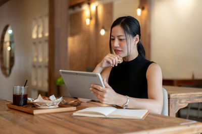 Young woman using mobile phone at table