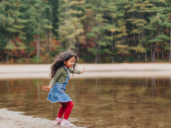 Girl playing by lake on a lovely autumn or fall day