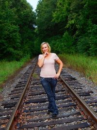 Full length portrait of woman standing on railroad track