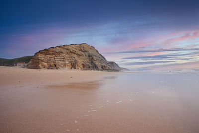 Rock formation on beach against sky
