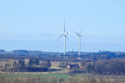 Windmills on field against sky