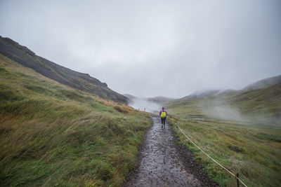 Rear view of woman walking on field during foggy weather