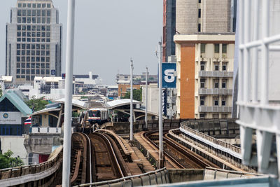 Train on railroad tracks by buildings in city