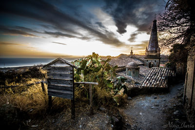 Panoramic shot of building by sea against sky during sunset